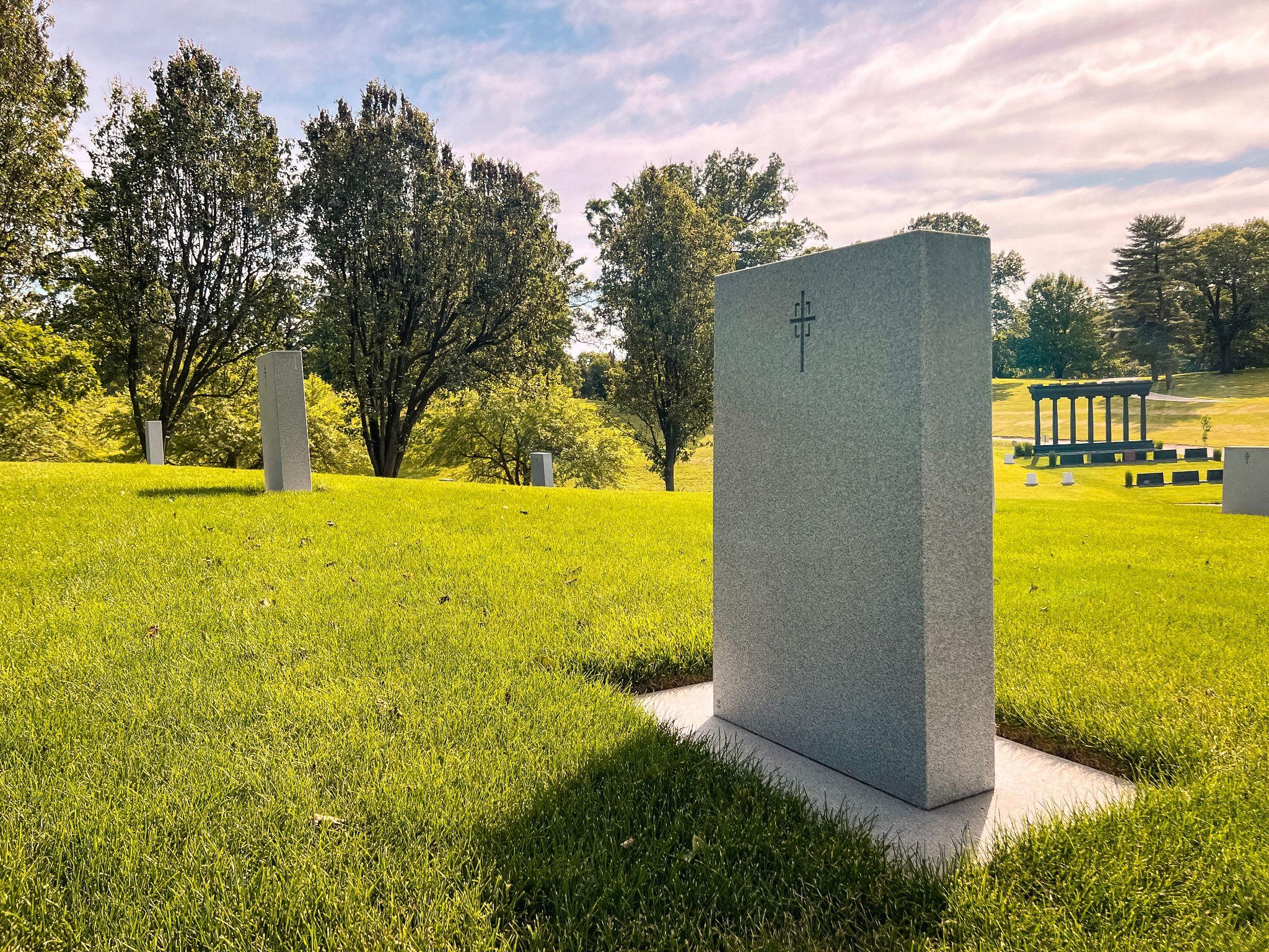How to choose a headstone Upright granite headstone in a green cemetery lined with trees